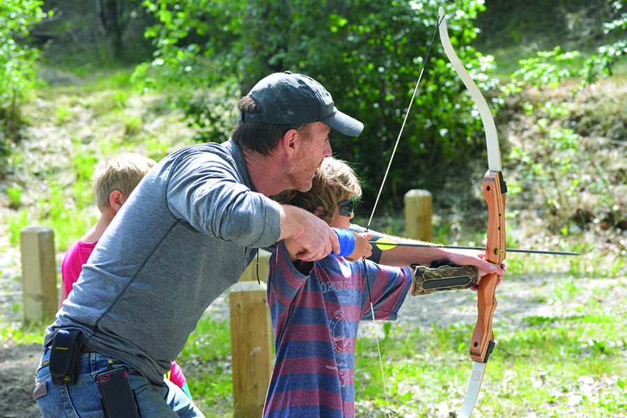 Event Organizer Clayton Gast passing on a few tips about shooting a bow and arrow to youngster Ty Godlonton.